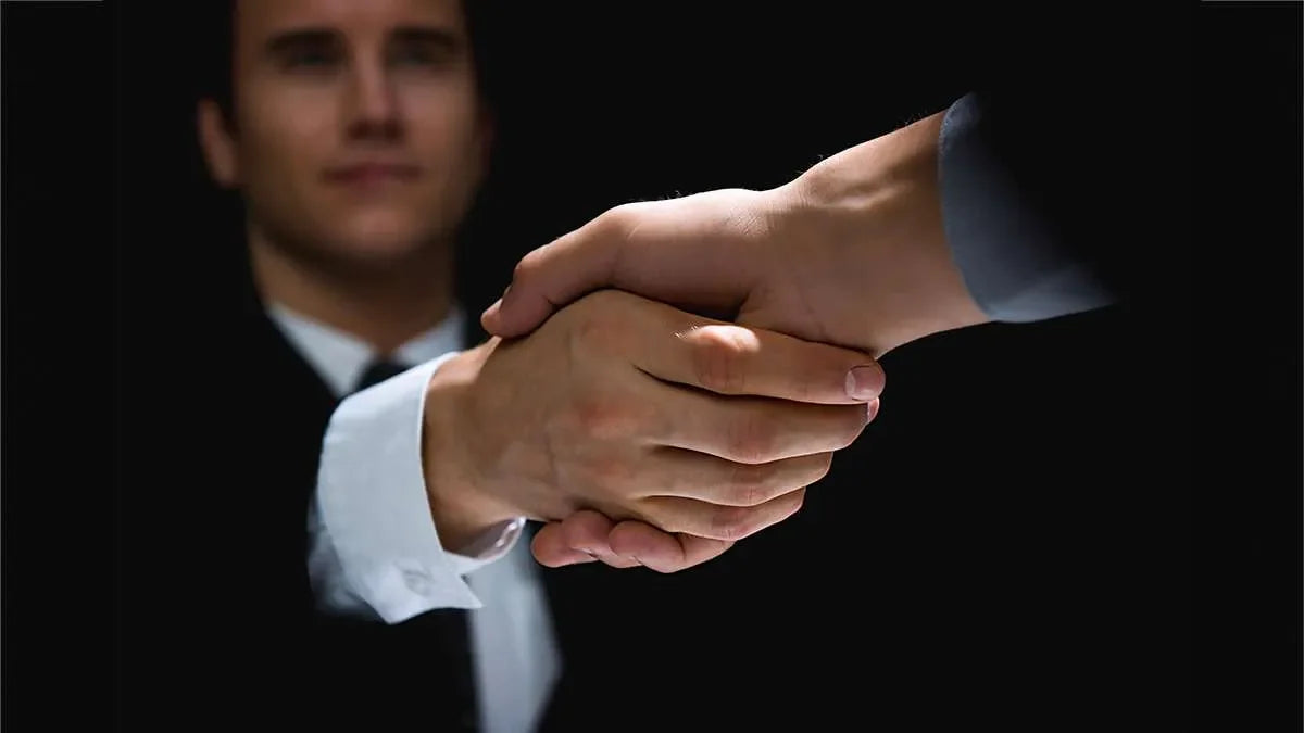 Stretta di mano tra investigatore privato e cliente per la consegna della documentazione di indagini concluse