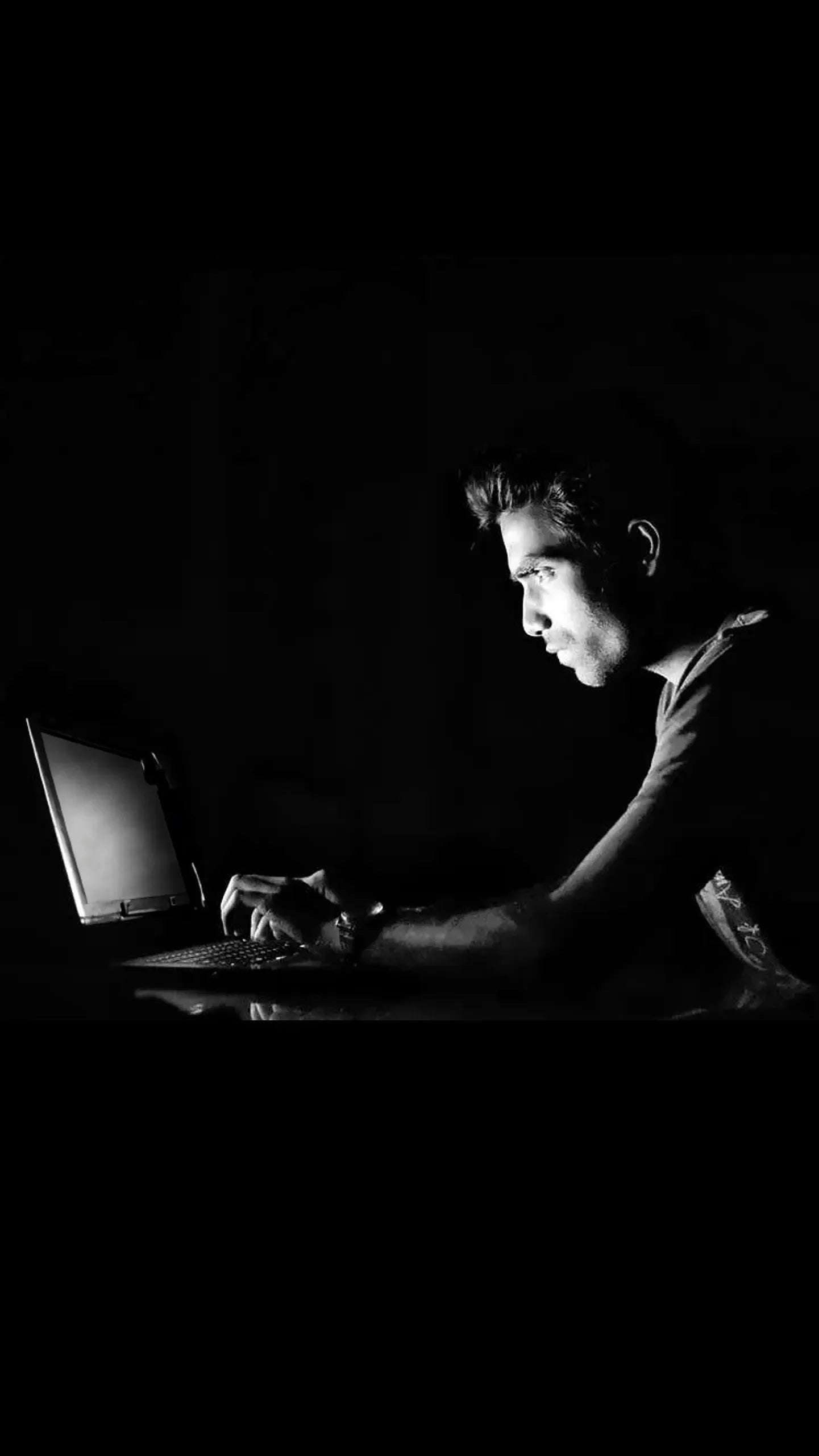 Foto in bianco e nero di un ragazzo che lavora al computer con massima riservatezza per delle indagini private