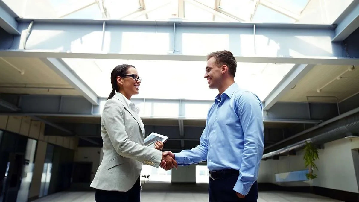 Uomo e donna si stringono la mano in accordo per un servizio di indagine aziendale