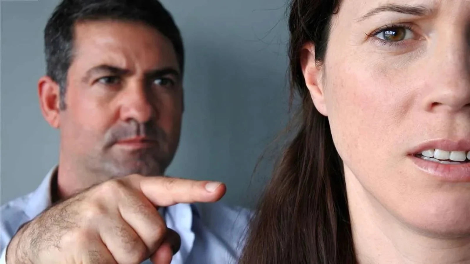 Uomo indica con rabbia una donna preoccupata, simbolo di separazione con addebito e conflitto coniugale.