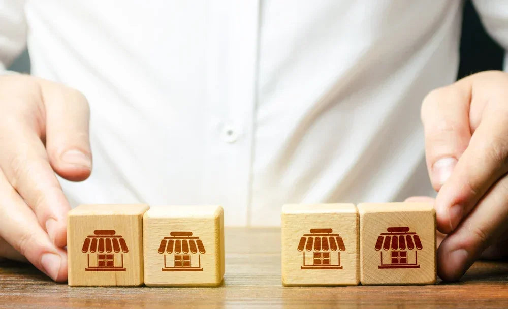 Cubi di legno con icone di negozi rappresentano franchising e filiali, simbolo di verifica tramite il servizio di indagini Mistery Shopping