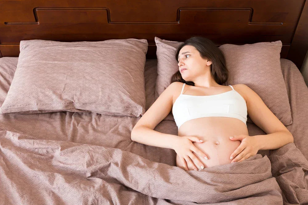 Donna incinta sola a letto, simbolo di abbandono del tetto coniugale e disagio familiare.