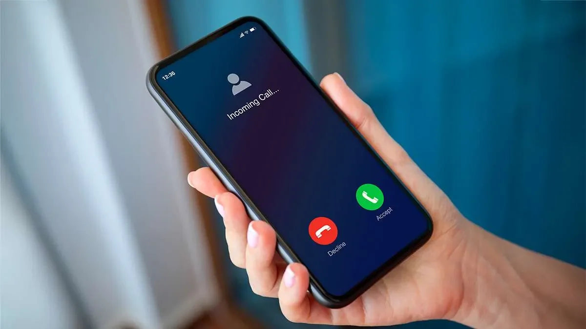 Mano che tiene smartphone con chiamata in arrivo, simbolo di bonifica telefonica e sicurezza delle comunicazioni.