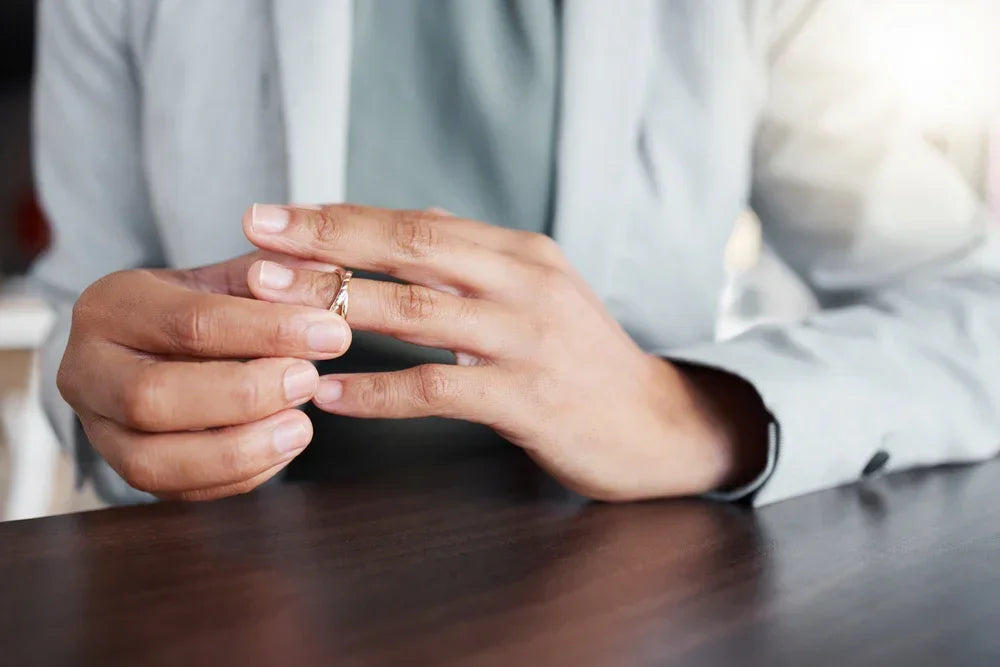 Mani di un uomo in giacca tolgono dal dito la fede nuziale. Simbolo di cambiamenti improvvisi nello stile di vita.