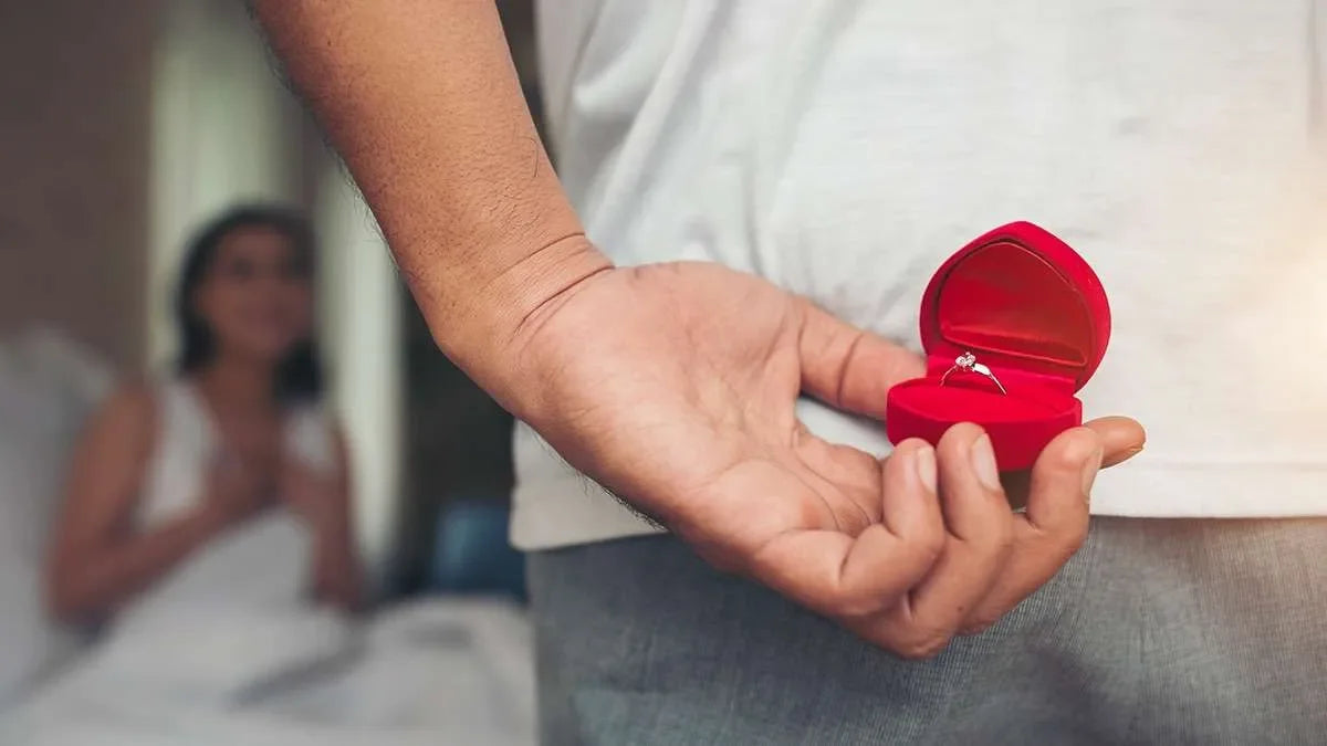 Mano maschile nasconde un anello nuziale dietro alla schiena con la sposa su sfondo sfocato. Simbolo di indagini prematriminiali.