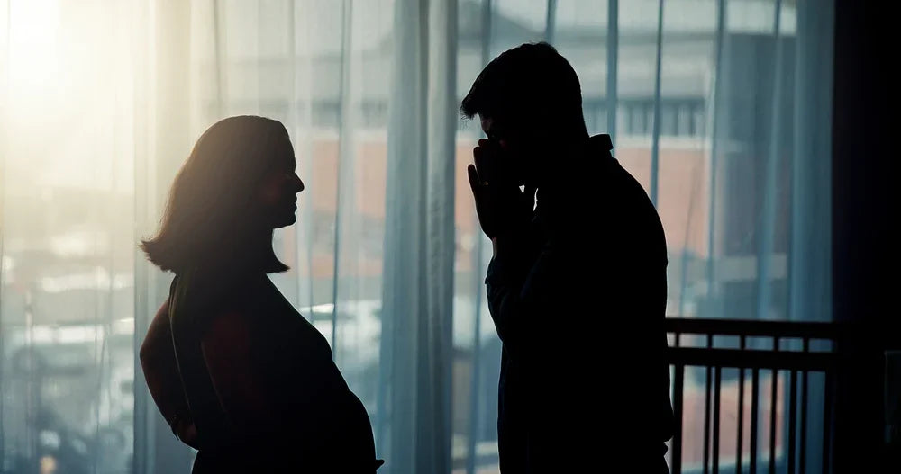 Coppia in controluce con tensione emotiva, simbolo di sospetti e infedeltà coniugale.