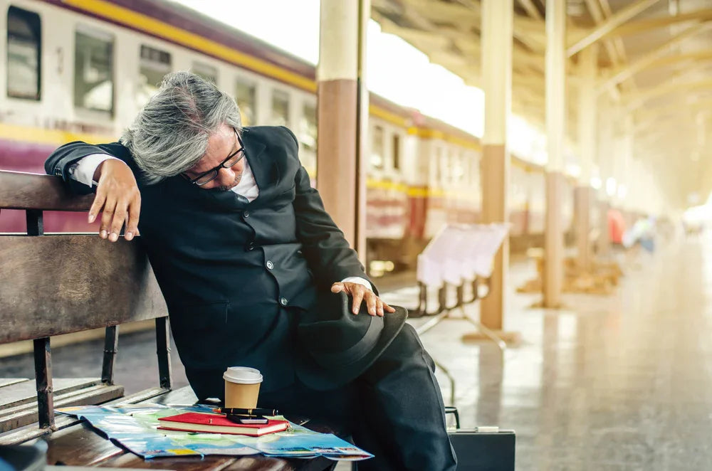 Uomo in stato alterato seduto sulla panchina di una stazione ferroviaria. Simbolo di indagini per scomparsa improvvisa legata a debiti o disagio psicologico.