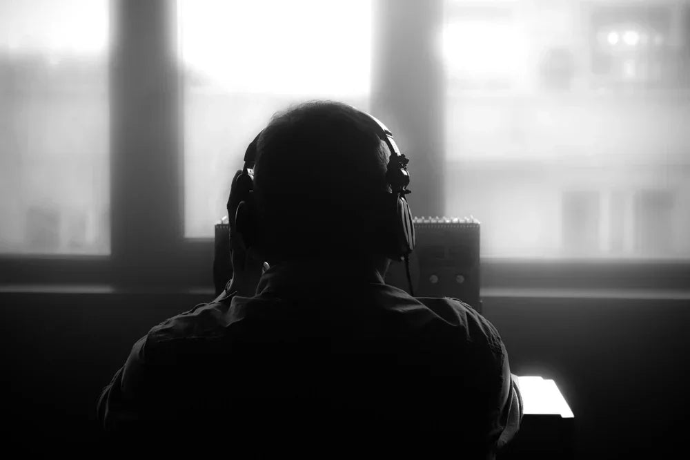 Operatore con cuffie effettua intercettazioni ambientali in ufficio, simbolo di monitoraggio telefonico e investigazioni tecniche.